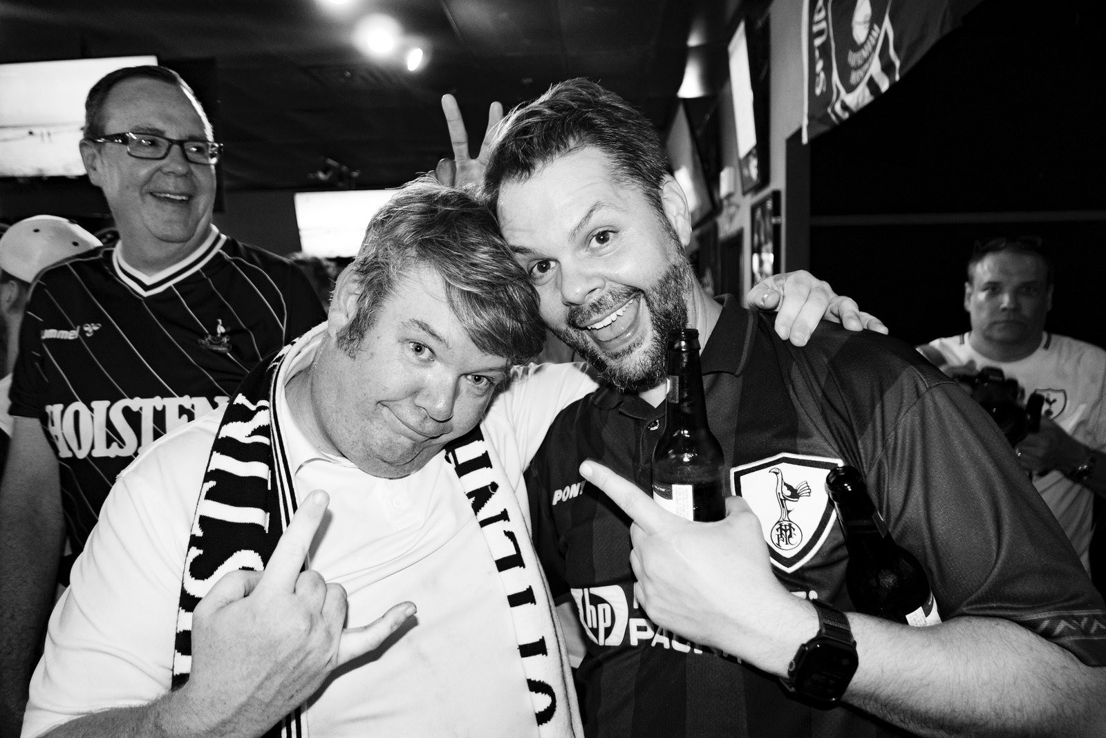 Two Austin Spurs supporters in Tottenham shirts and a scarf, grinning at the camera inside Mister Tramps.